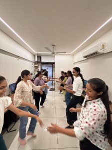 Employees performing Garba dance in the office during celebration.